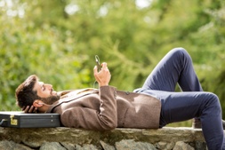 Young business man relaxing using smartphone outdoor in nature